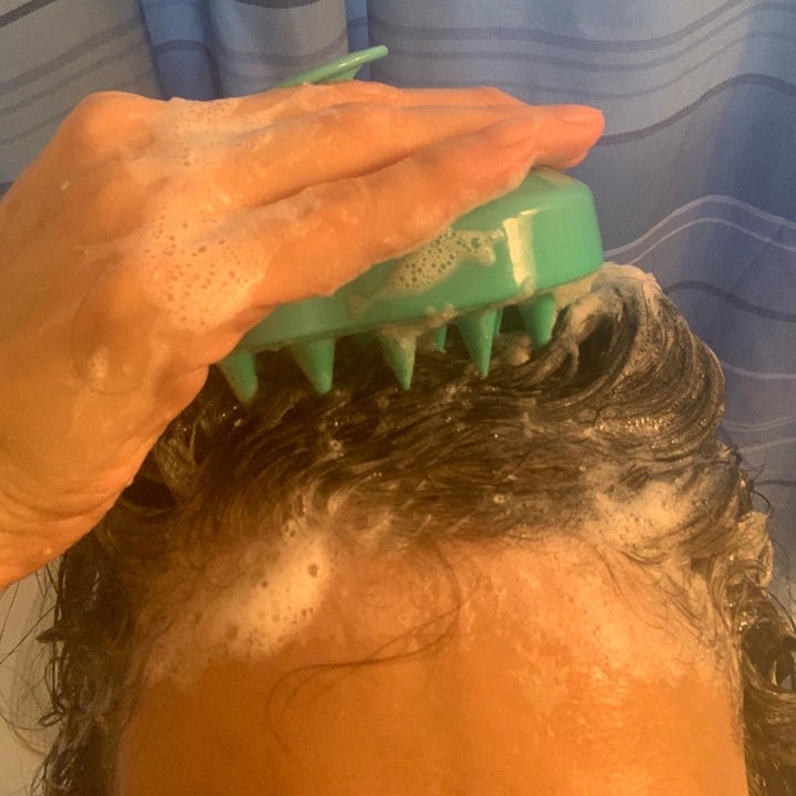 reviewer using the massager on their head with soap and water