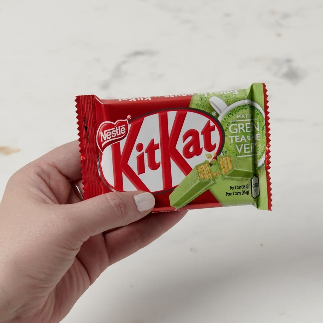 A person holding a small KitKat matcha