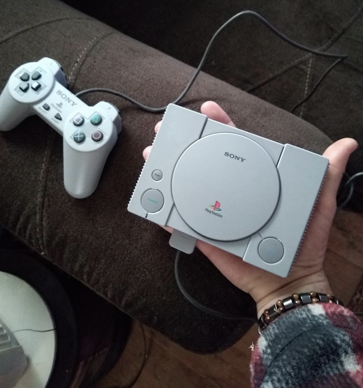 hand holding the compact console containing the games with a normal controller