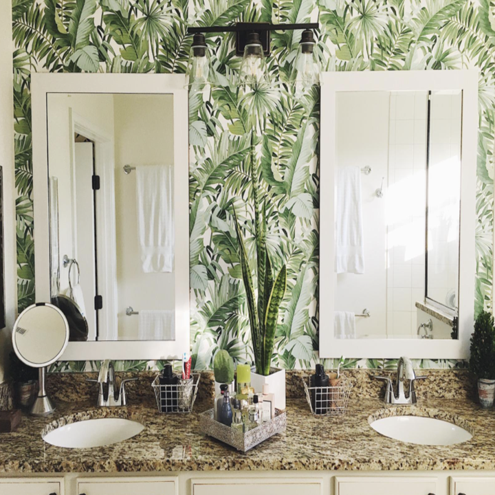 reviewer's bathroom counter with the wallpaper up behind two his-and-hers mirrors