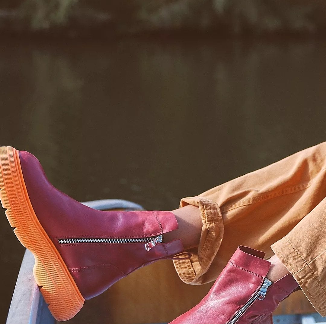 cushy boots with a large orange sole and red top. the sides zip up.