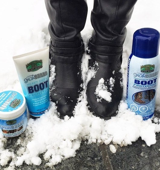 a pair of boots covered in snow next to a bottle of the protective spray