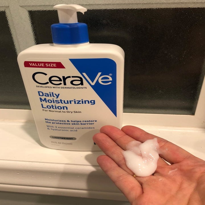 a reviewer photo of the moisturizer bottle and a hand with some of the shit, creamy lotion on it