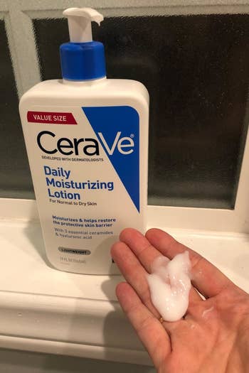 a reviewer photo of the moisturizer bottle and a hand with some of the shit, creamy lotion on it