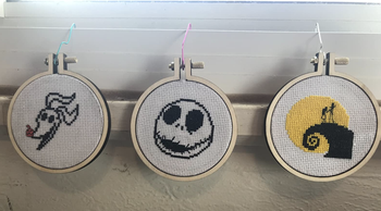 A customer review photo of three completed cross-stitch patterns
