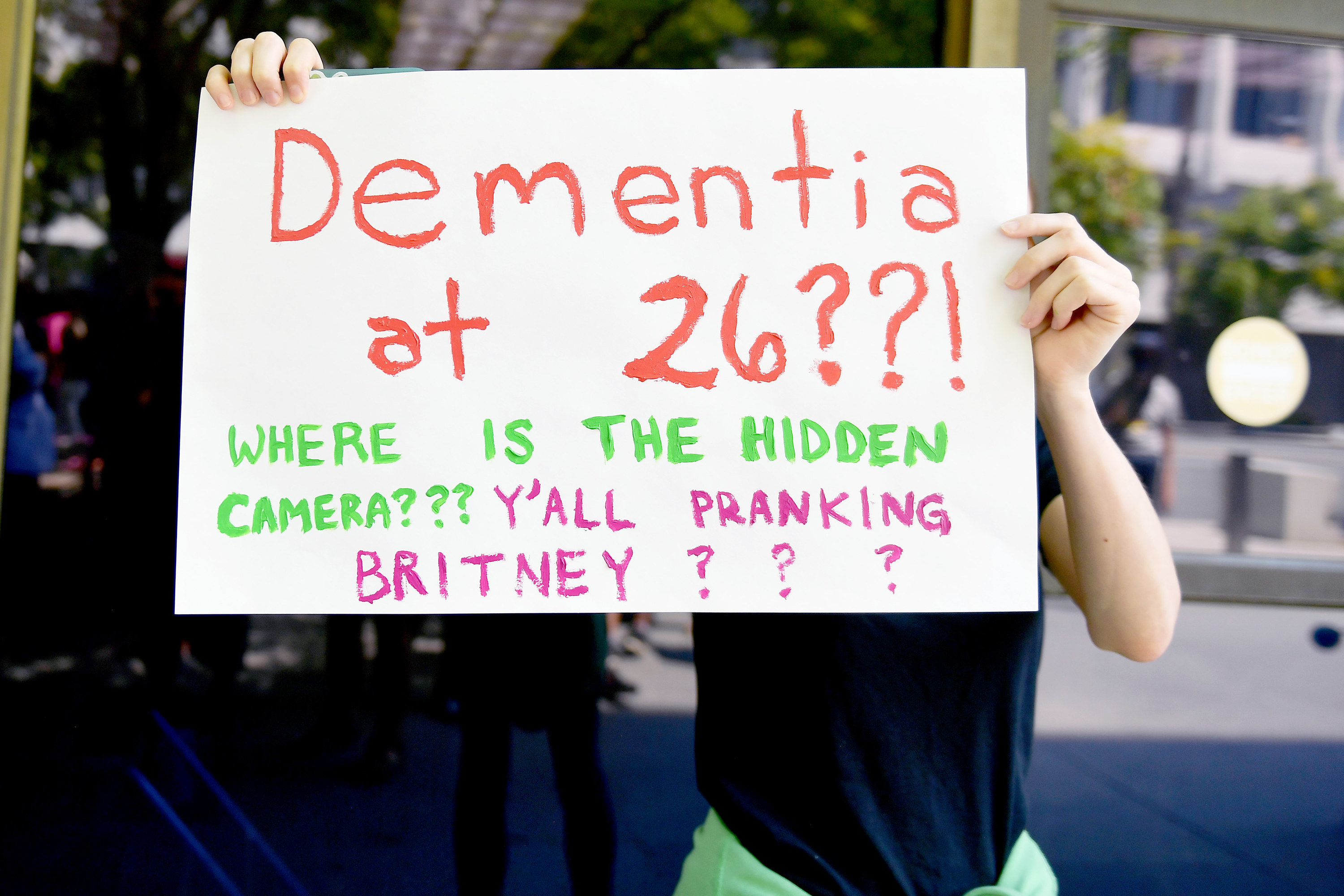 A protester holds a sign that reads &quot;dementia at 26? where is the hidden camera? y&#x27;all pranking Britney&quot;