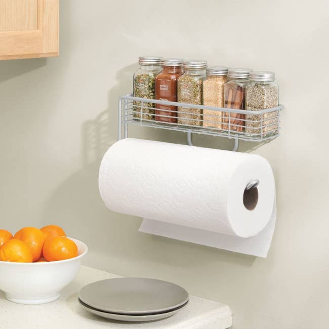 the paper towel holder on a wall with spices on the shelf