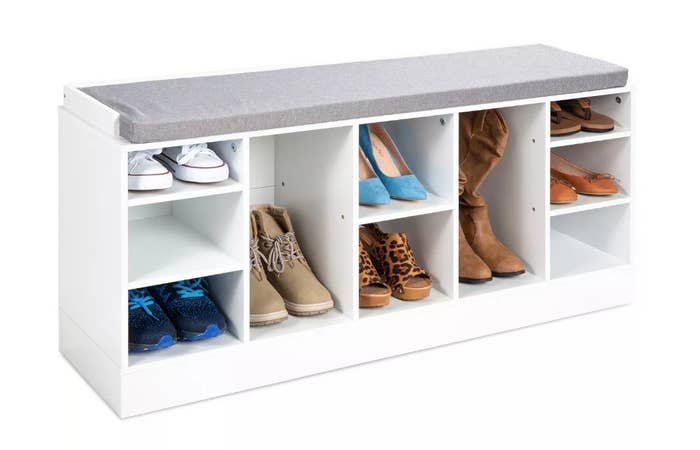 A white shoe storage bench with a grey cushion top
