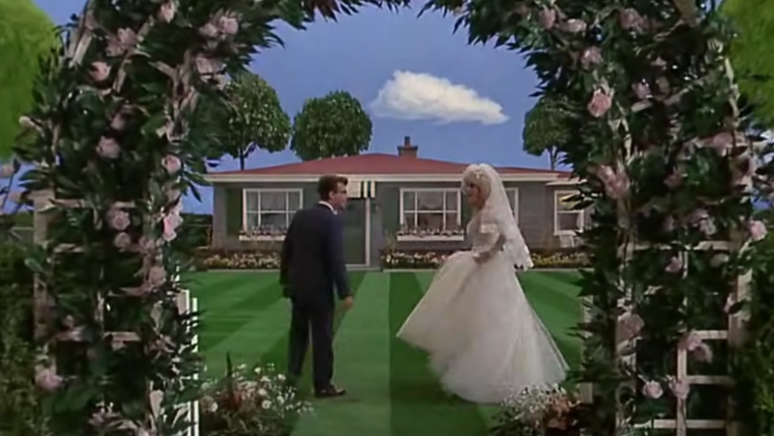 Seymour and Audrey walking towards a cute house in suburbia, dressed in a suit and wedding dress respectively