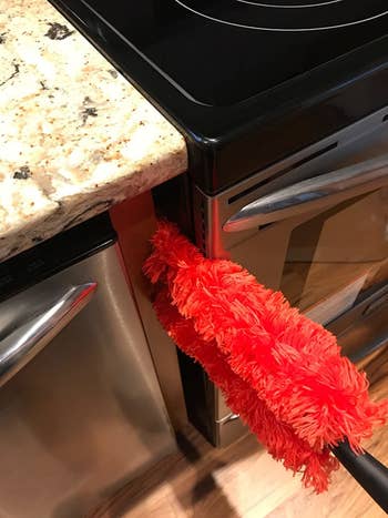 the duster being used between a dishwasher and stove