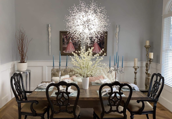 reviewer photo of a dining room with the chandelier glowing a cool light above the table