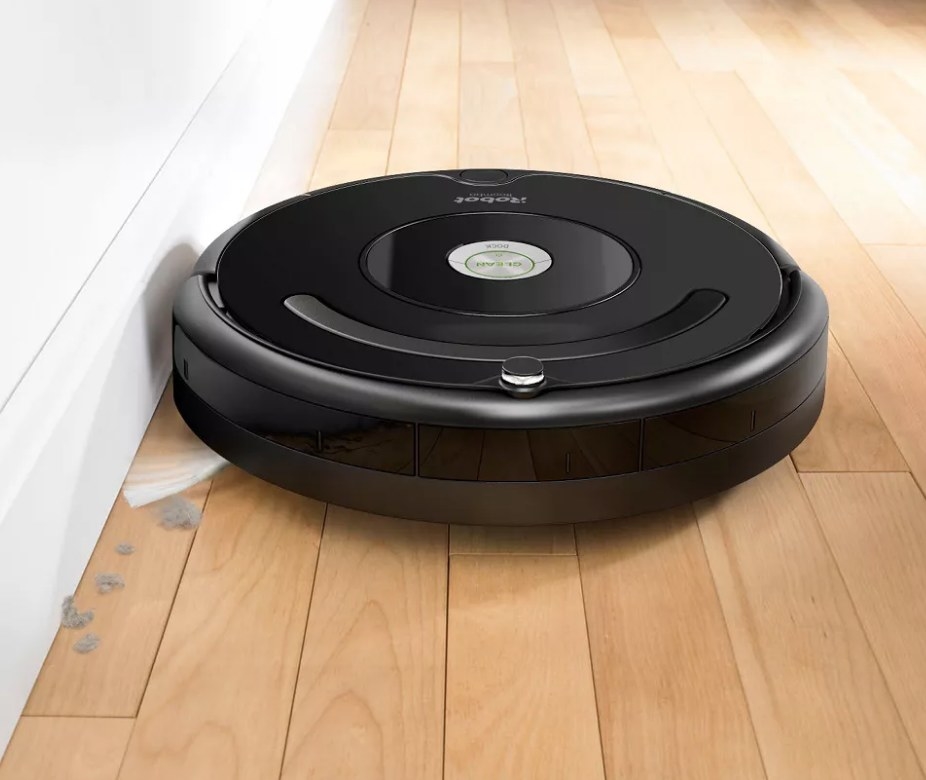 A iRobot Roomba vacuum cleaning dust on a wood floor