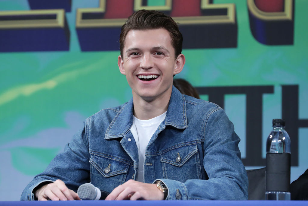 Tom Holland smiling and wearing a denim jacket