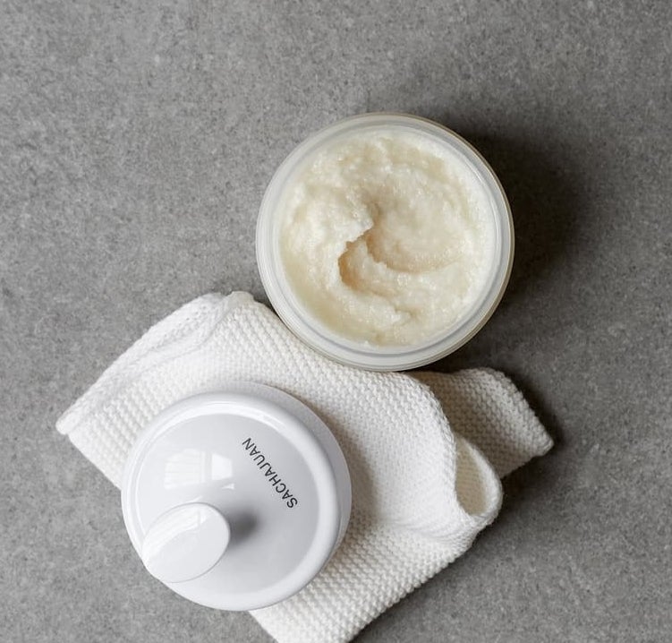 an open jar of the scalp scrub on a waffle towel, next to the scalp brush