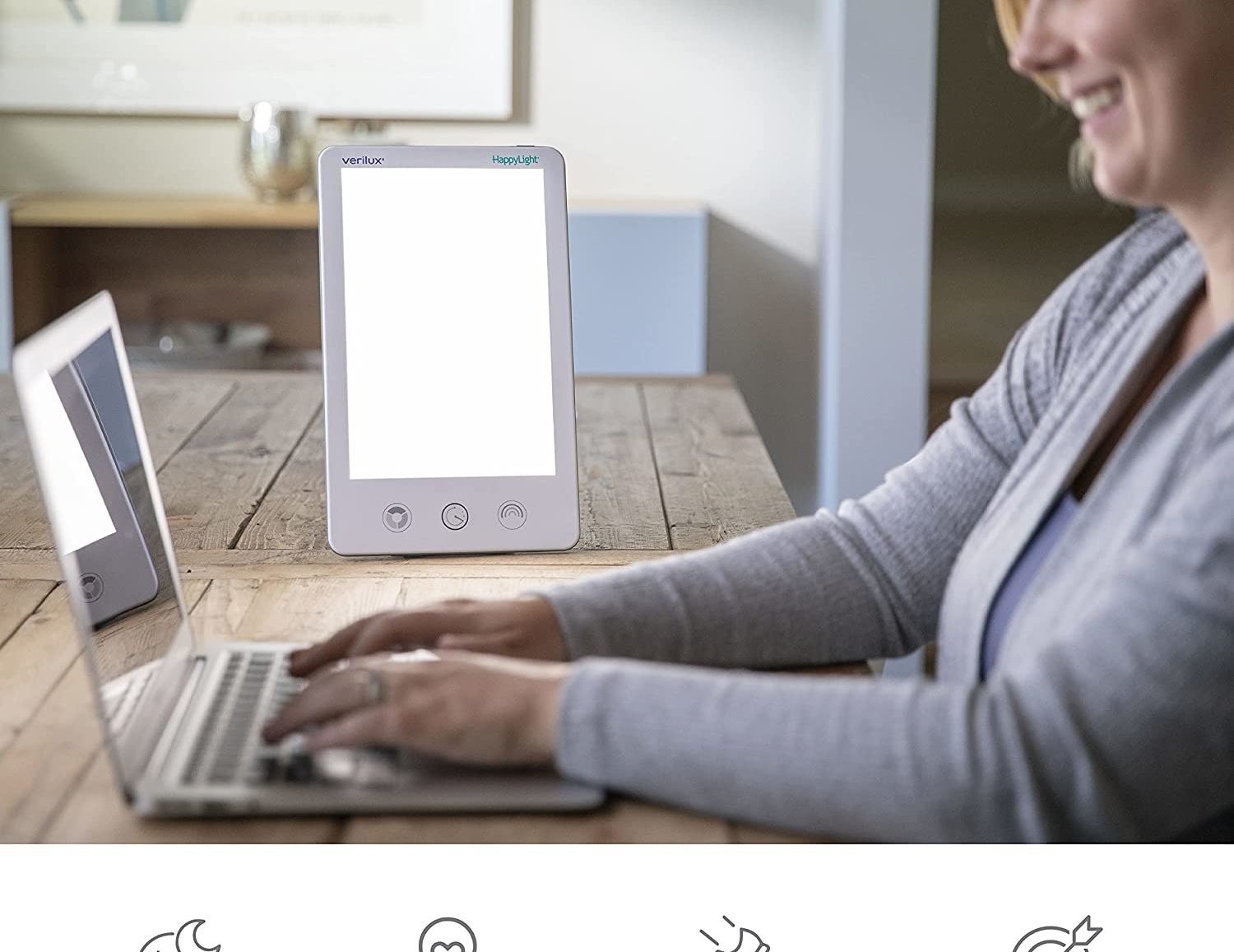 someone working at a laptop while sitting next to the light therapy lamp