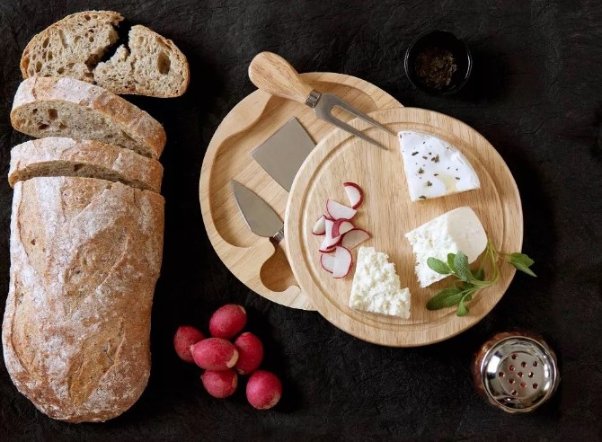A round cheese board with knife storage below