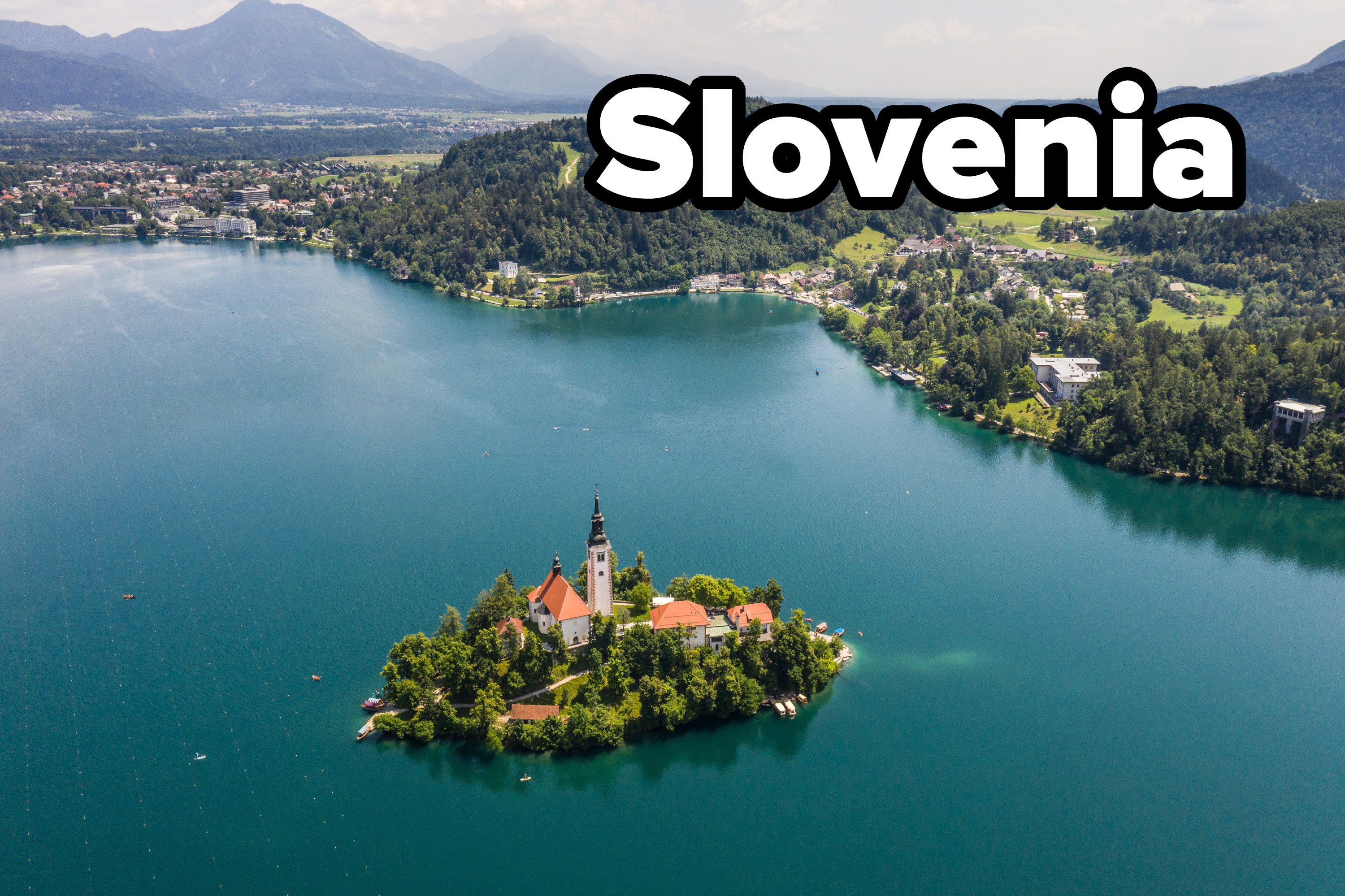 Lake Bled in Slovenia with small island in the center of the lake that has a church on it, with mountains in the background