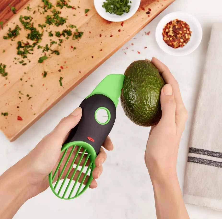 A model cutting an avocado with a 3-in-1 avocado slicer