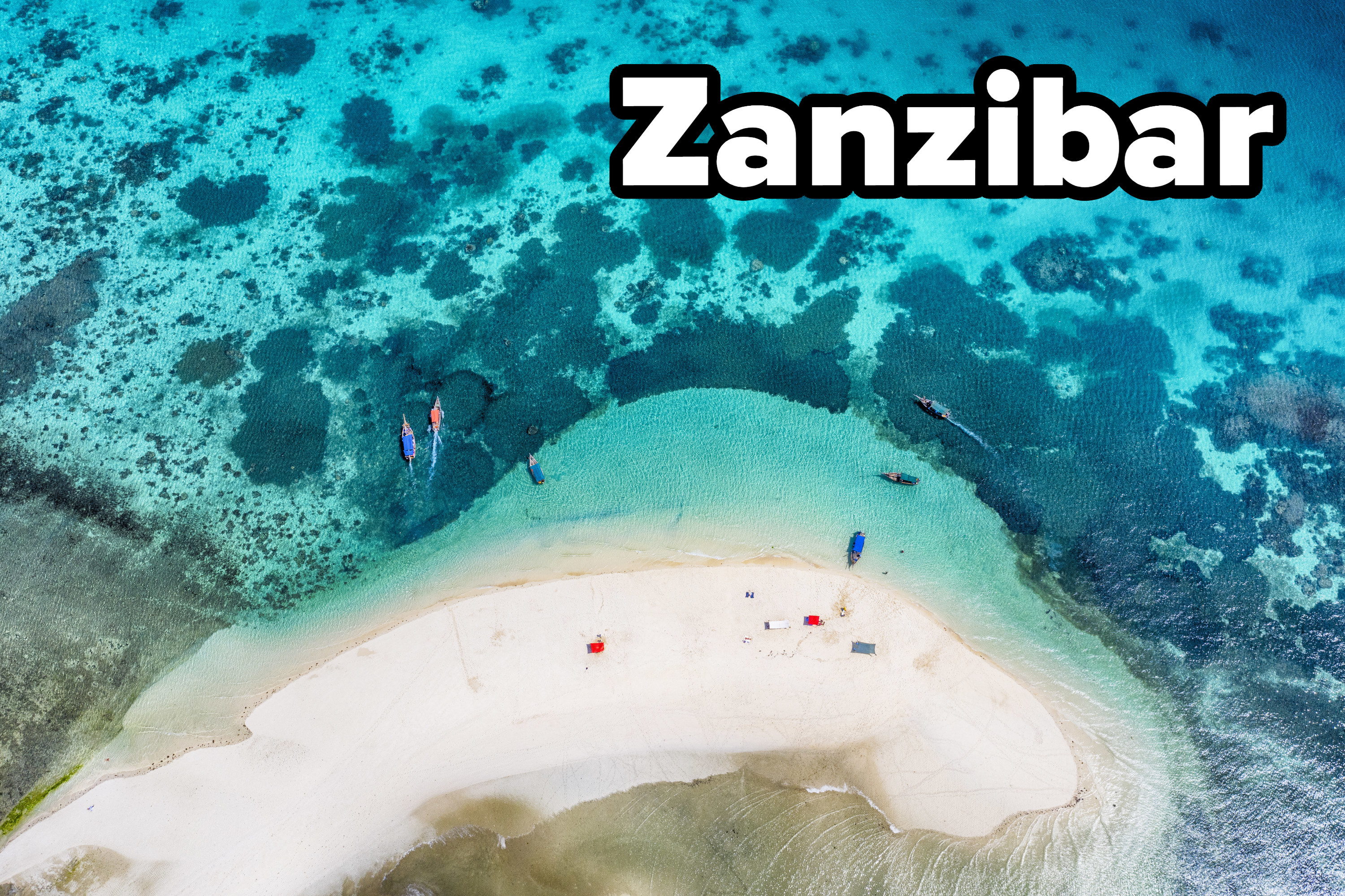 Aerial view of a small sandy island (sand bank) with tourist boats and tourists in the Indian Ocean. Location: Menai Bay, Zanzibar, Tanzania.
