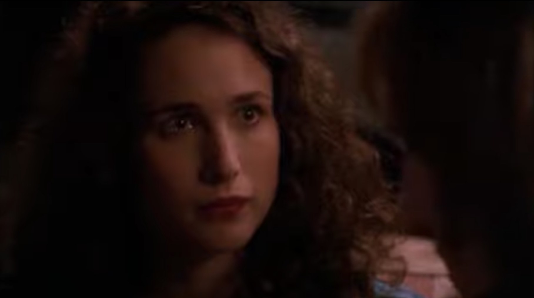 Andie MacDowell stares longingly at a man with his back to the camera.