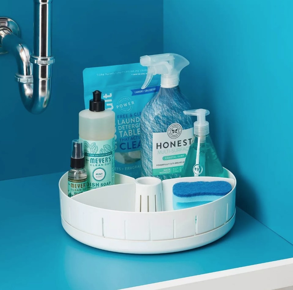 A white under-the-sink turntable filled with cleaning products