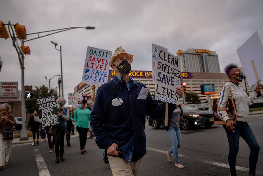 People march with signs that say clean syringes save lives