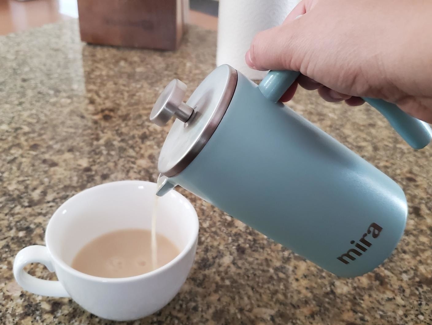 Reviewer is pouring coffee from the light blue French press into a cup