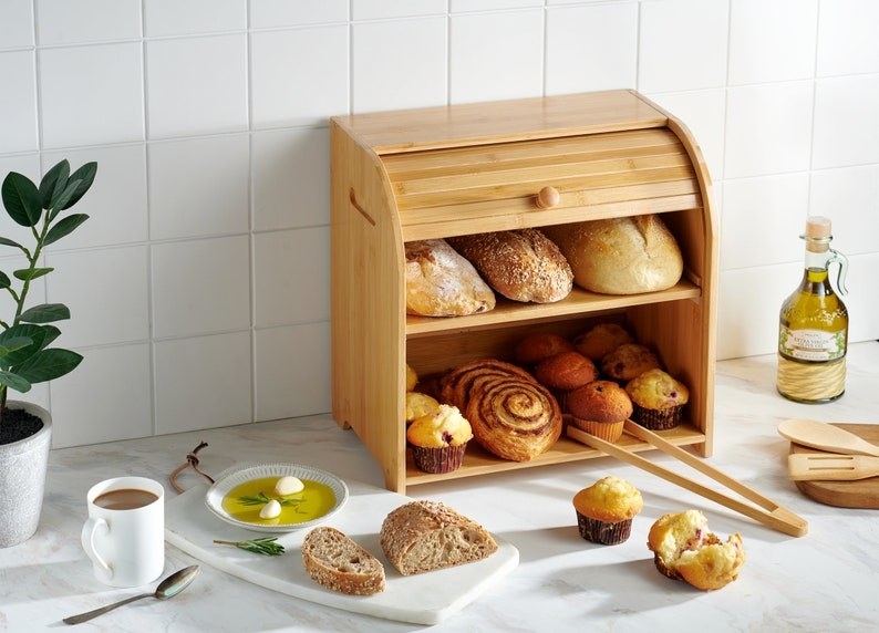 The light wooden bread box with two shelves full of baked foods and a sliding door