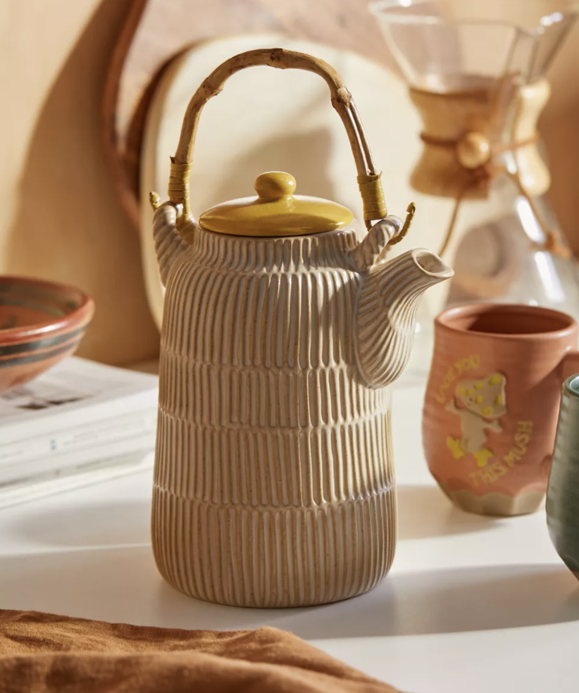 The ceramic coffee server in a beige color with vertical lines etched and a yellow lid