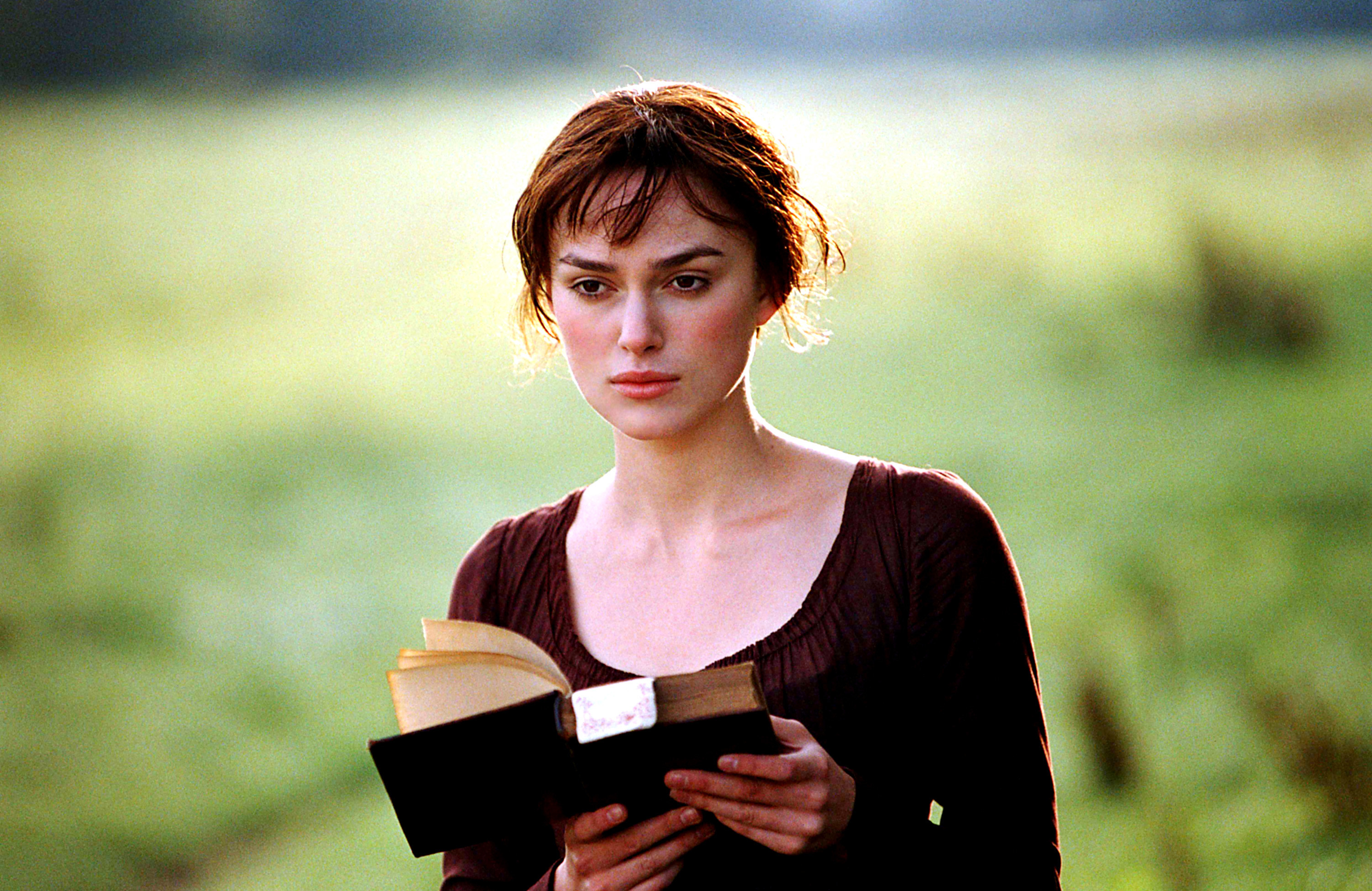 Keira Knightley as Elizabeth Bennet, walking through a field reading a book