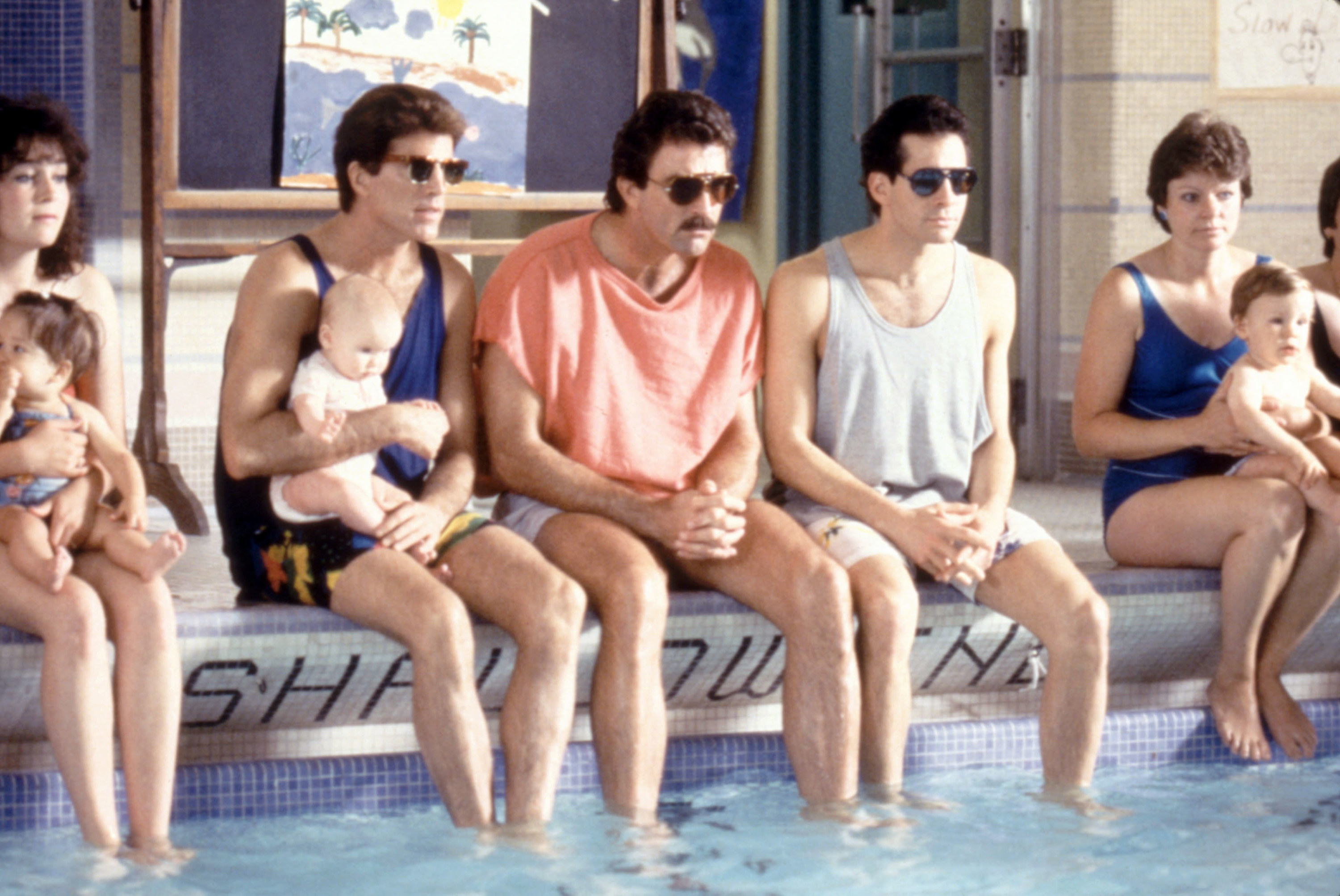 Ted Danson, Tom Selleck, and Steve Guttenberg sit together on the edge of a pool