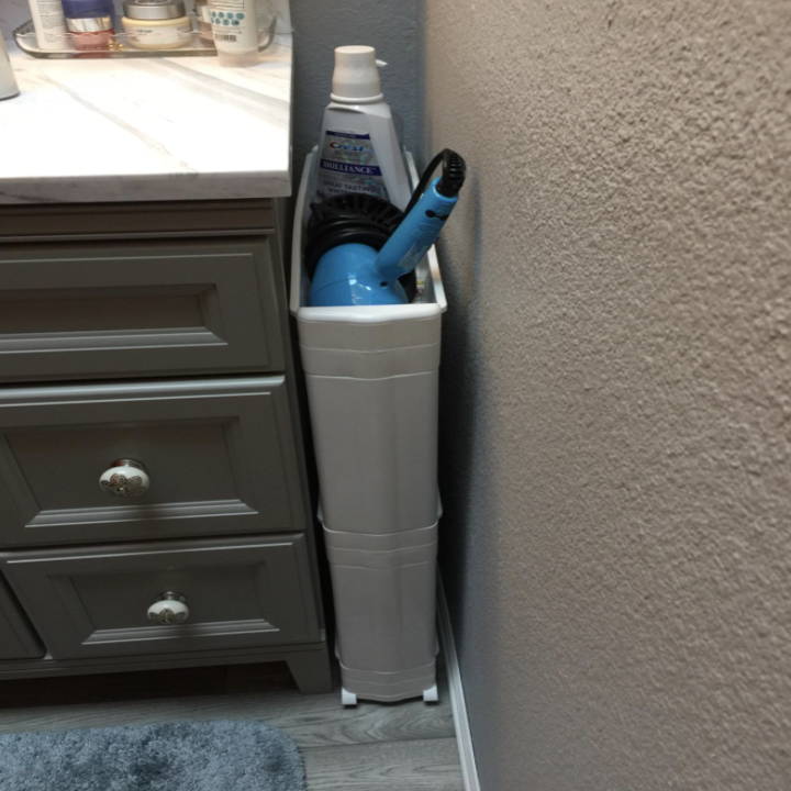 thin rolling shelf in between the wall and bathroom sink