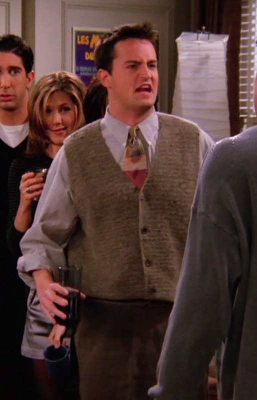 Chandler wearing pants, a sweater-vest, a tie, and a long-sleeved shirt