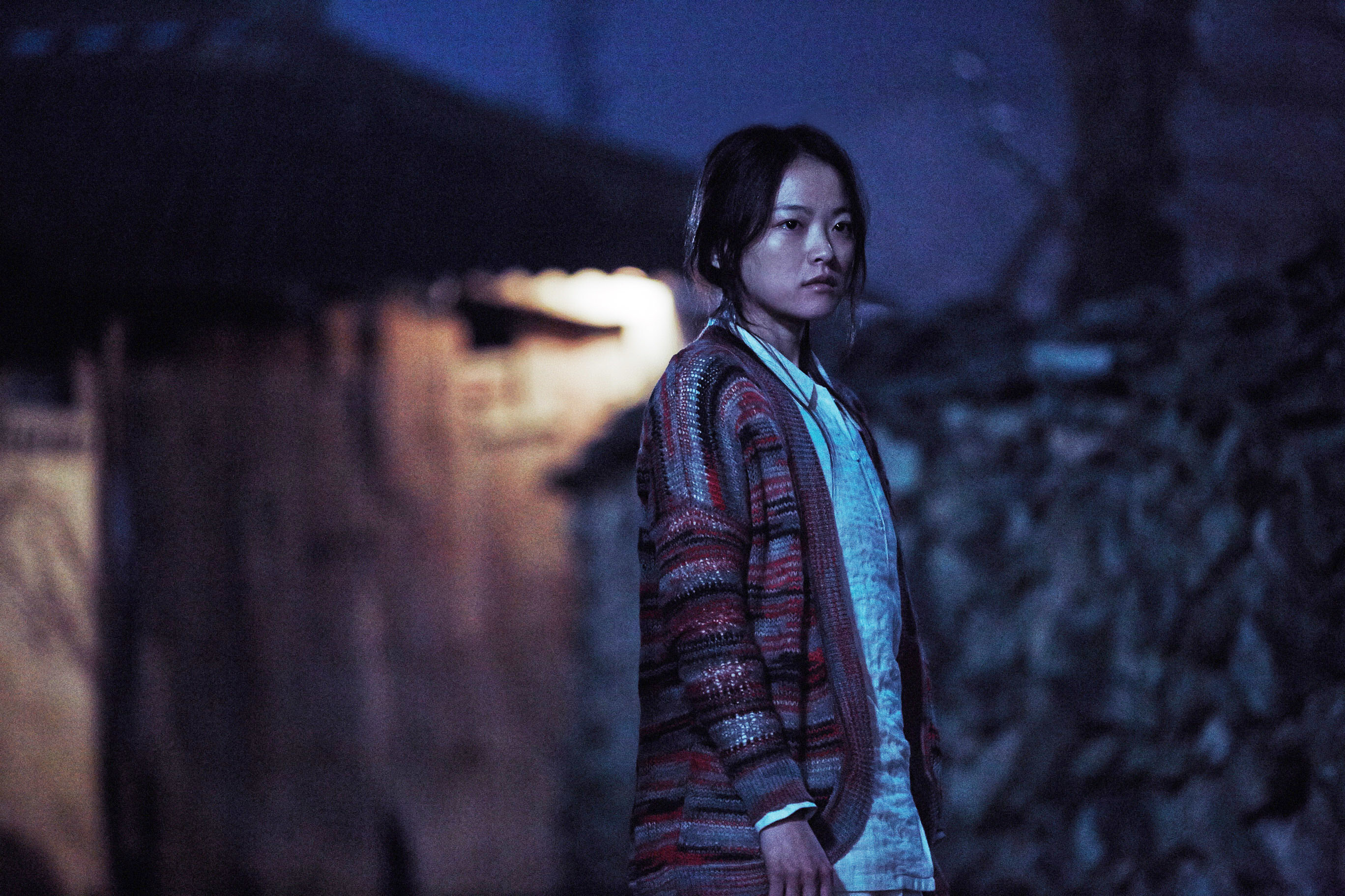 CHUN Woo-hee as Moo-Myeong, standing outside at night, wearing a sweater, and looking serious