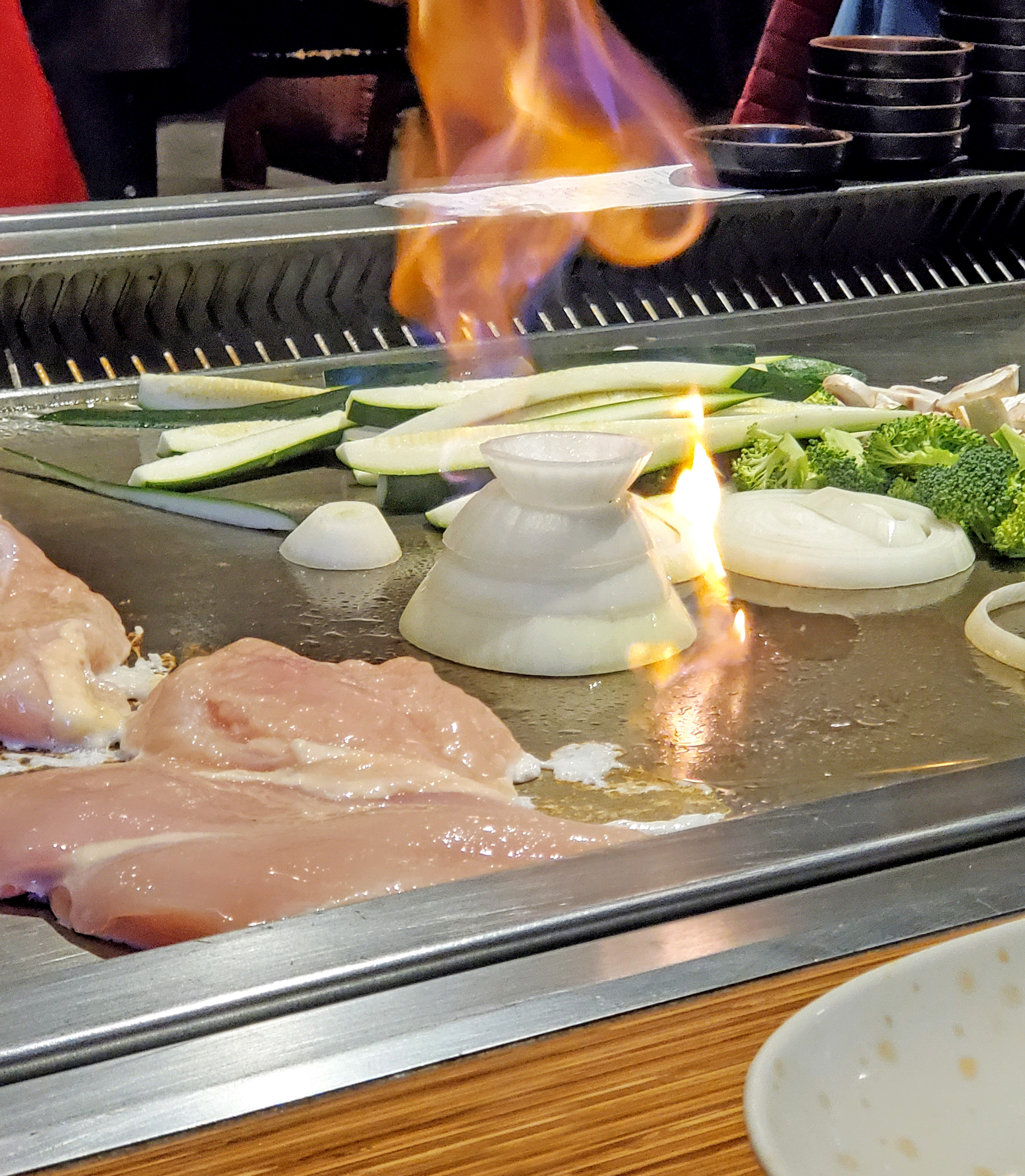 Various proteins and vegetables being cooked at a hibachi-style restaurant