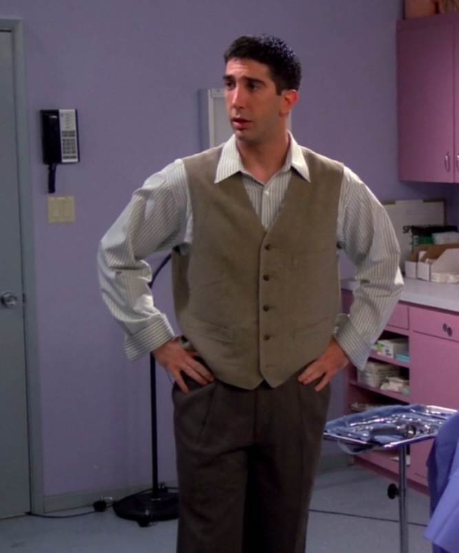 Ross wearing shoes, big pants, a long-sleeved shirt, and a vest and standing with his hands on his hips