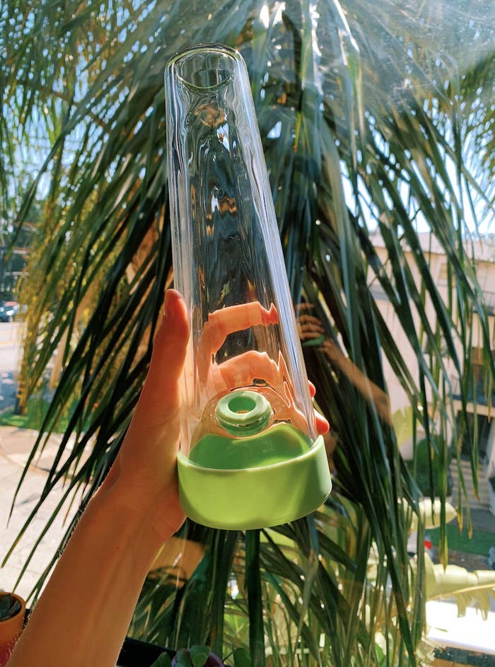 An image of the Session Goods Bong in Green held up in the author&#x27;s hand in front of a palm tree