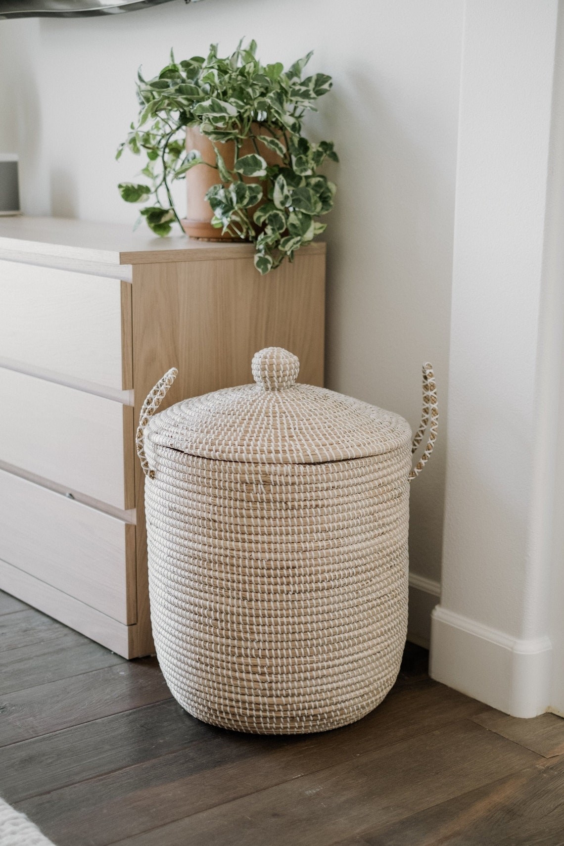 neutral light brown and white basket with handles next to chest of drawers