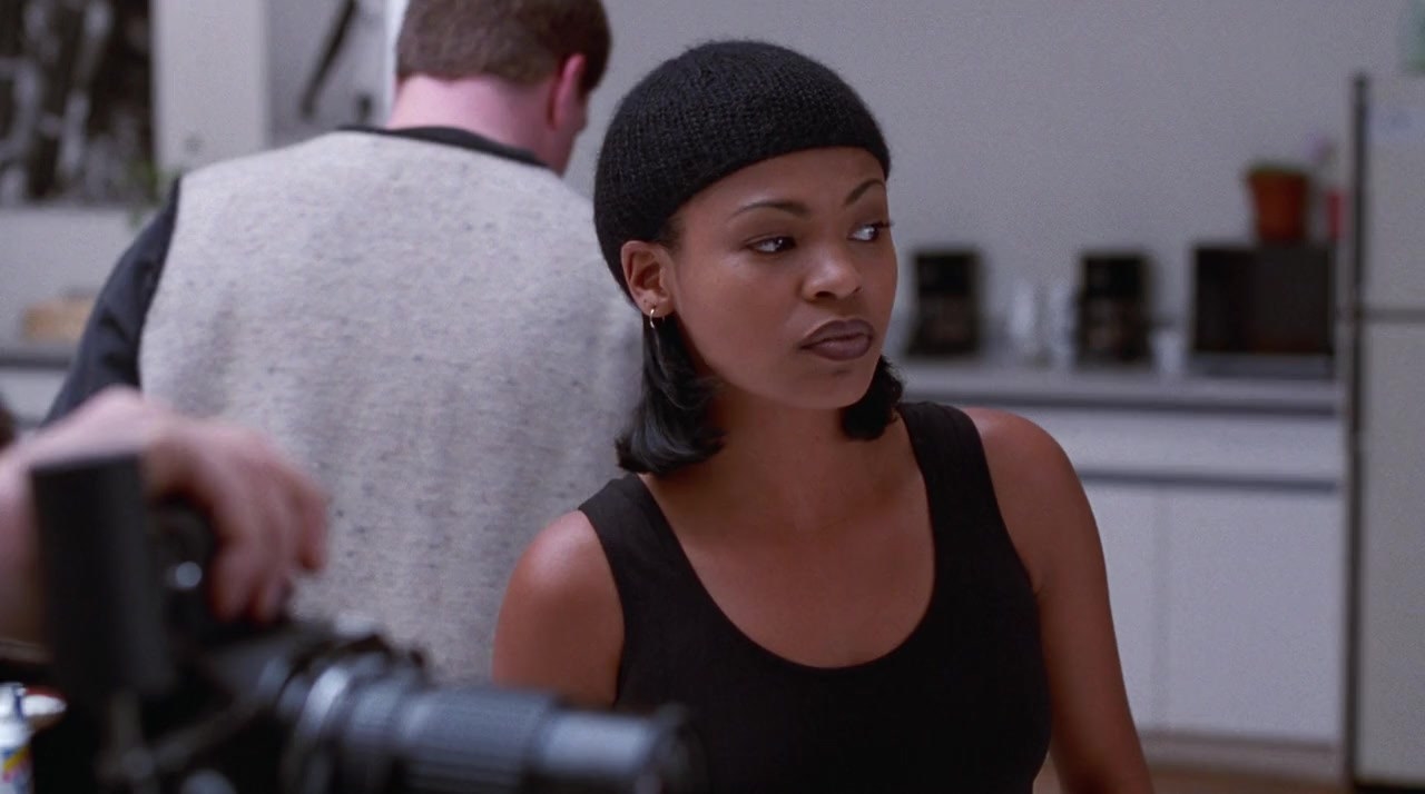 Nia Long looks away from the camera. She wars a black tank top and a black beanie on her head.