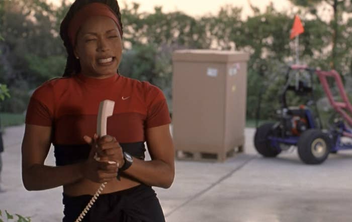 Actress Angela Bassett wears a reed crop top and looks excited while gripping a telephone.