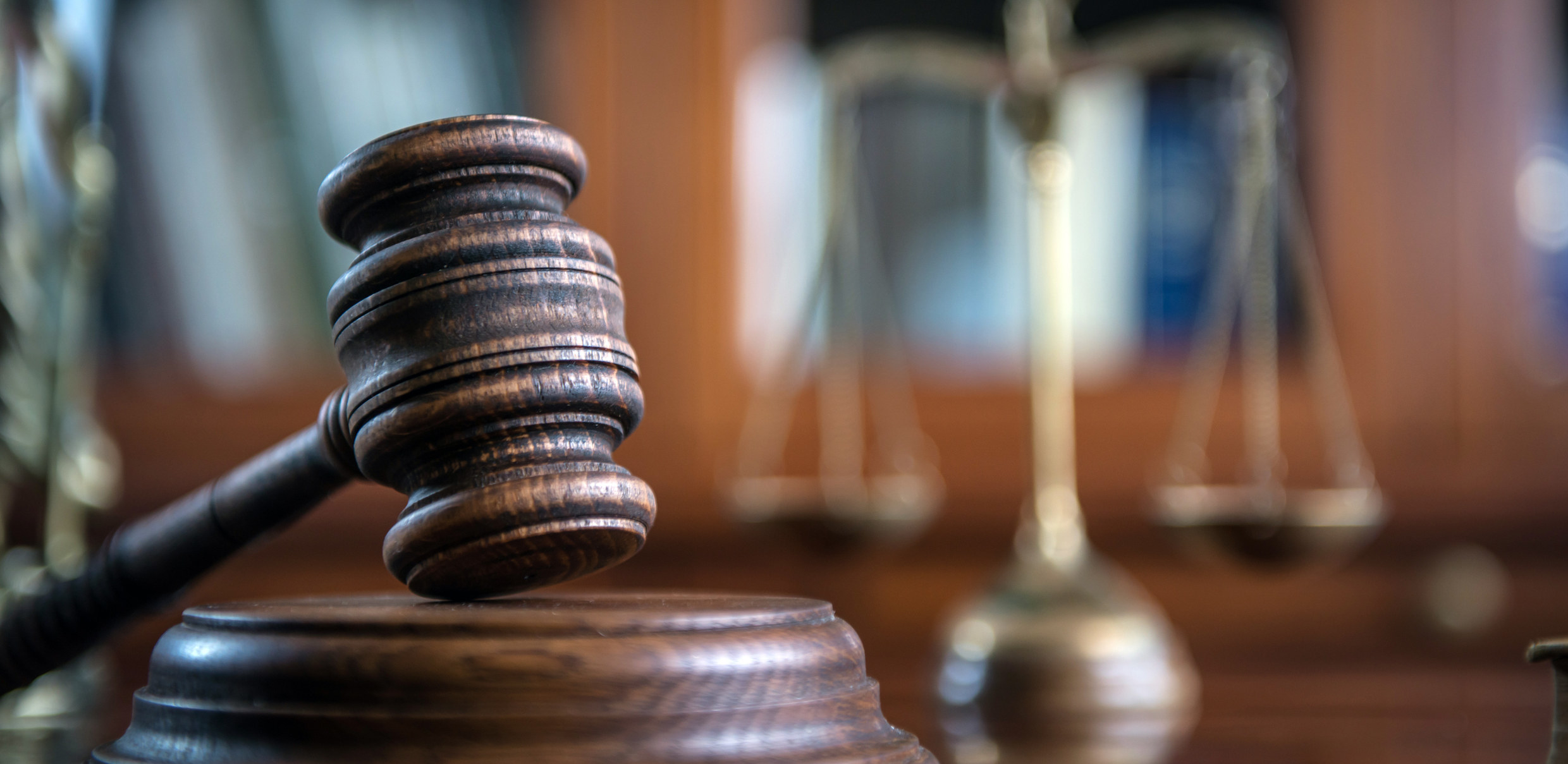 a judge&#x27;s gavel with a blurred balance scale in the background