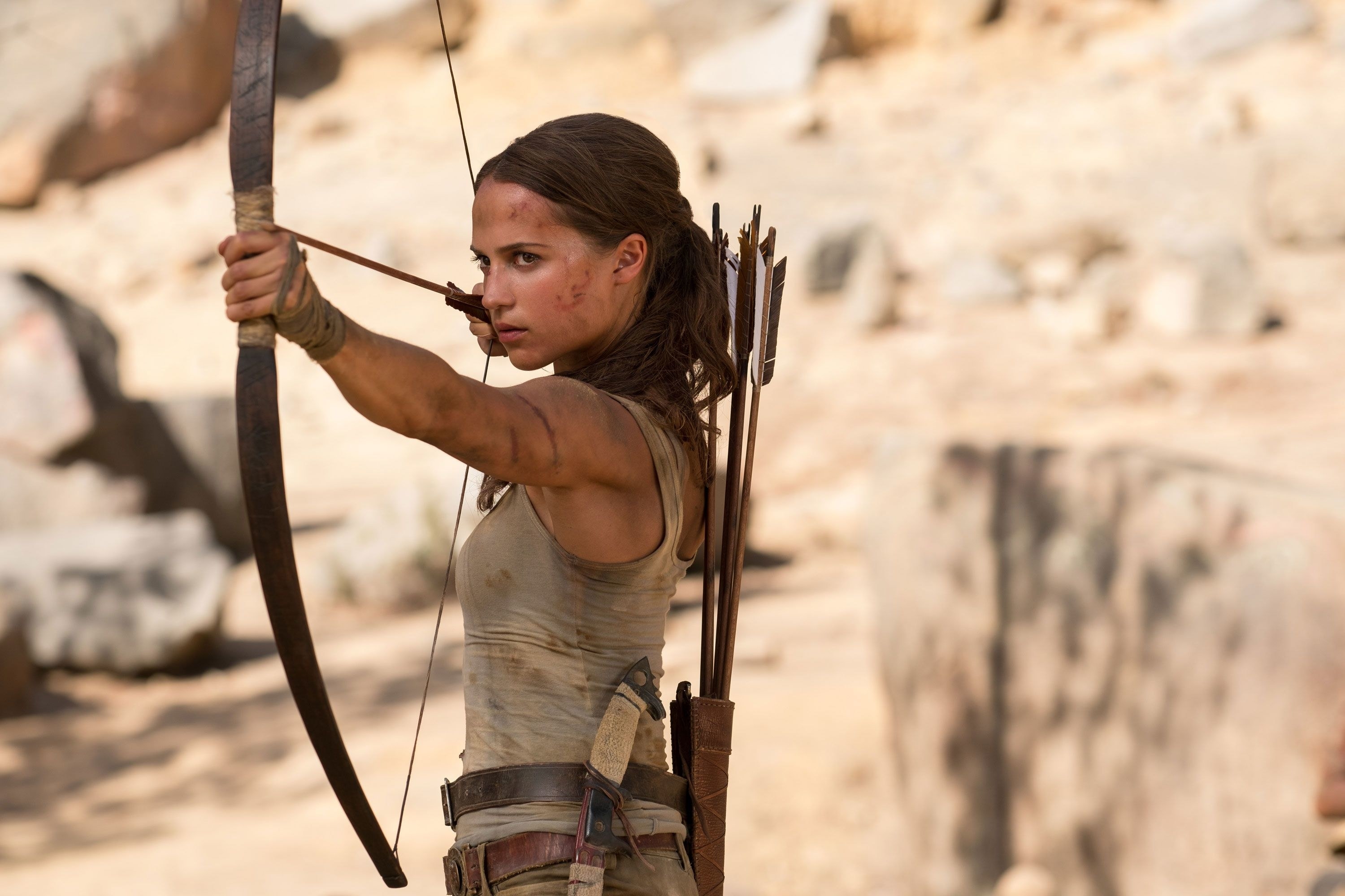 lara croft played by alicia vikander holds a bow ready to fire an arrow