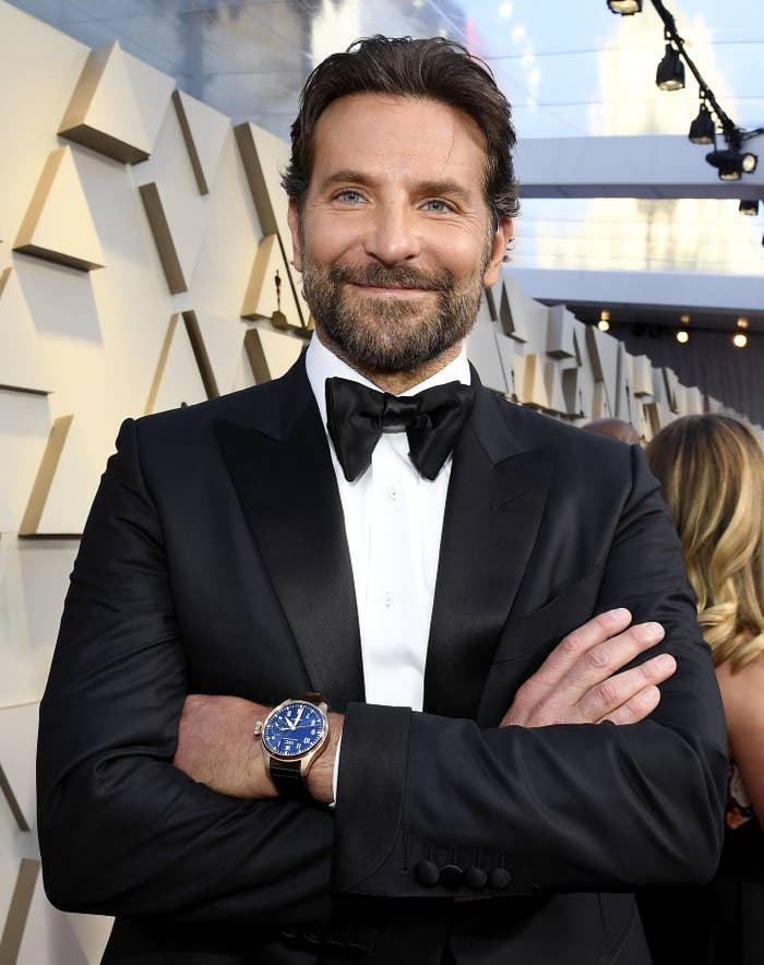 Bradley Cooper smiles with his arms crossed at an event