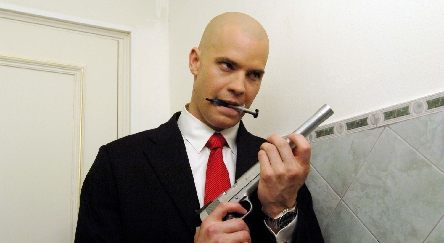 timothy olyphant as hitman puts a silencer on his pistol