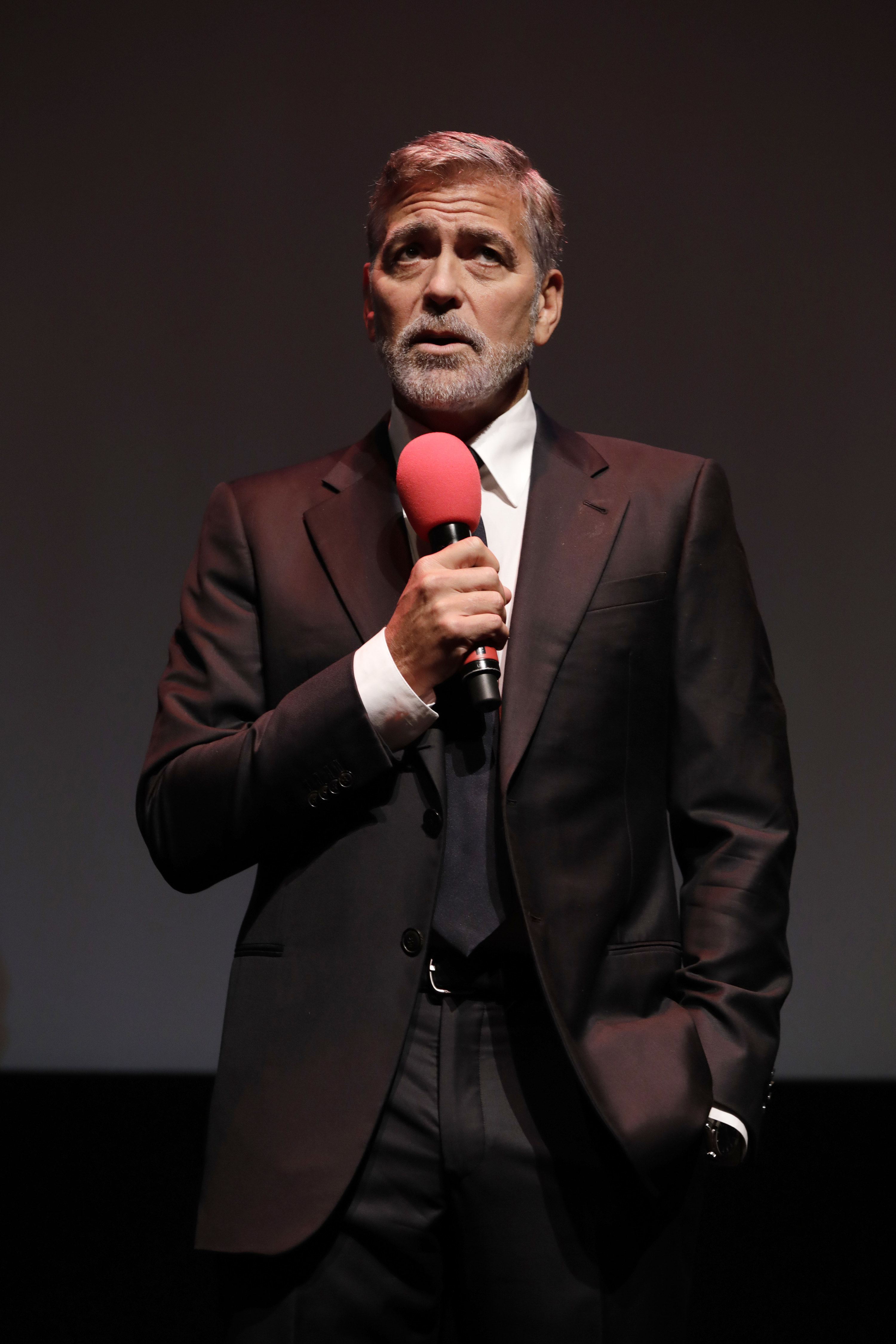Clooney speaks into a red microphone