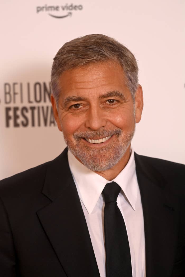 Clooney smiles for a photo while wearing a suit and tie