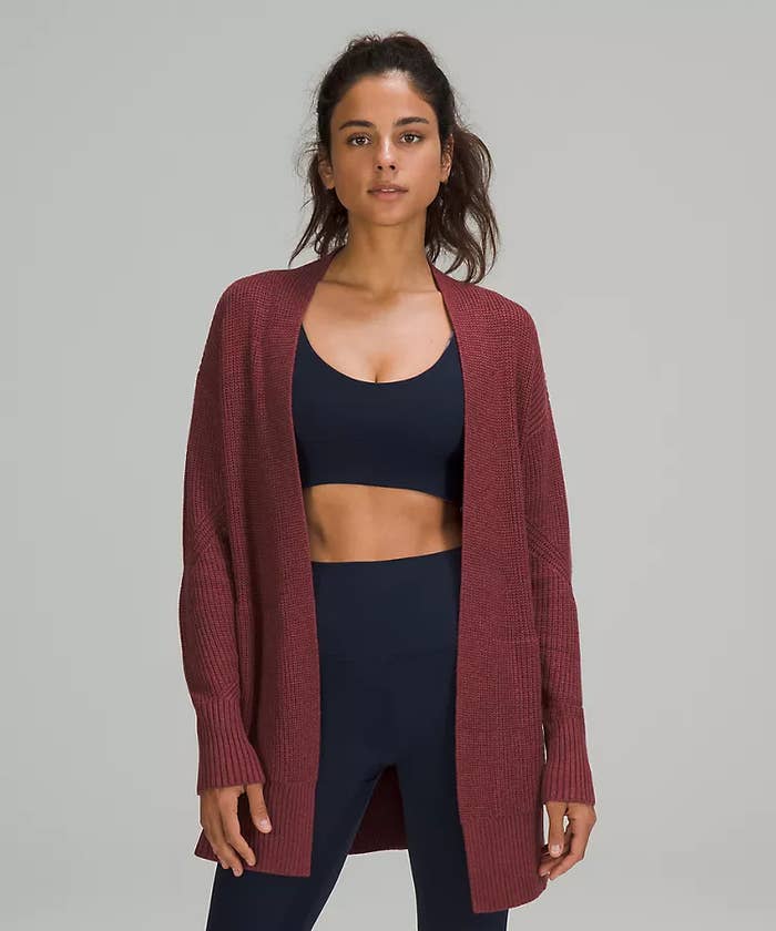 A person wearing a cardigan over a sports bra and leggings