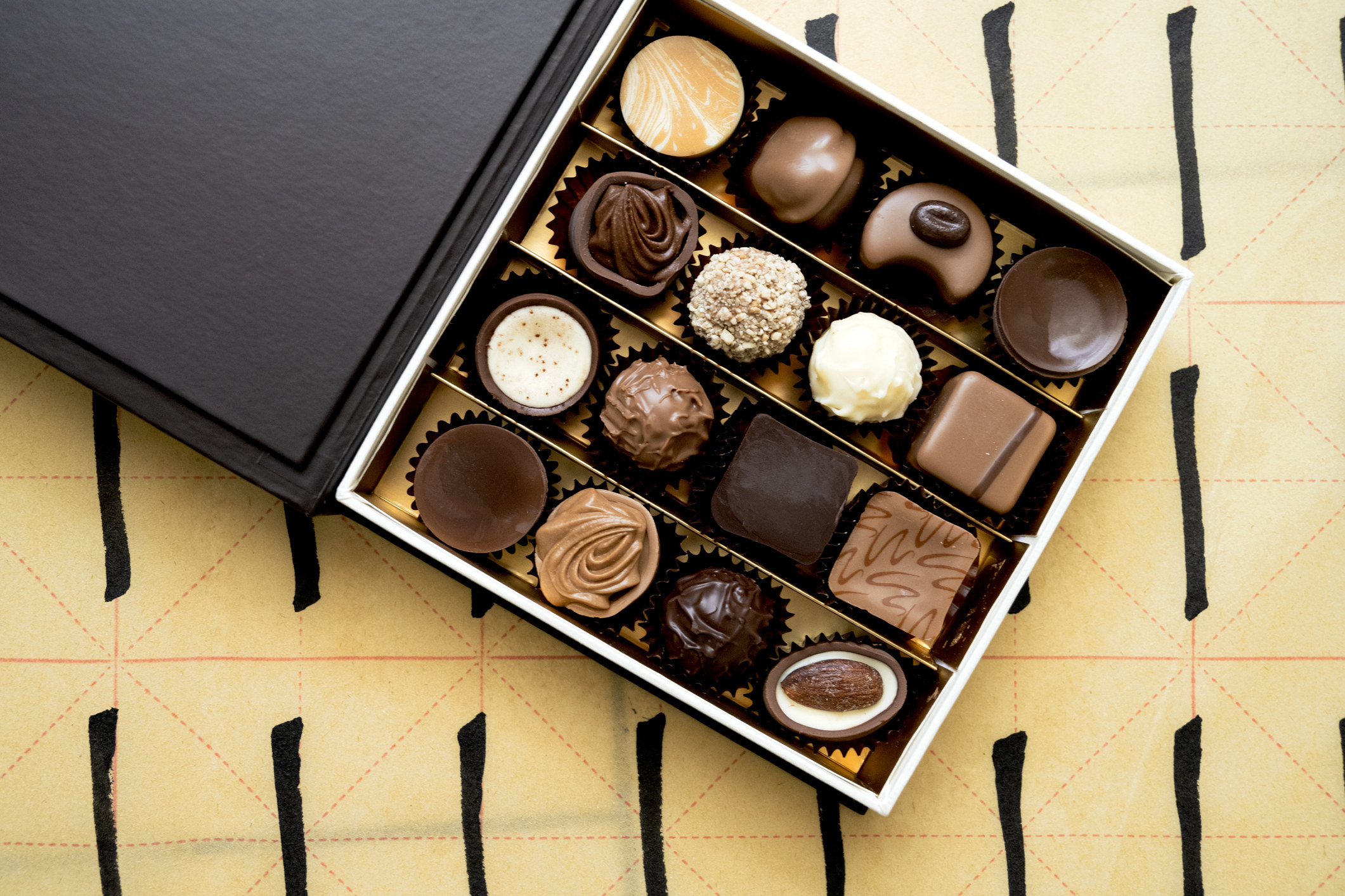 On a table lays a box of assorted chocolates.