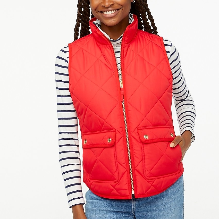 Model wearing a red puffer vest over a striped tee with jeans
