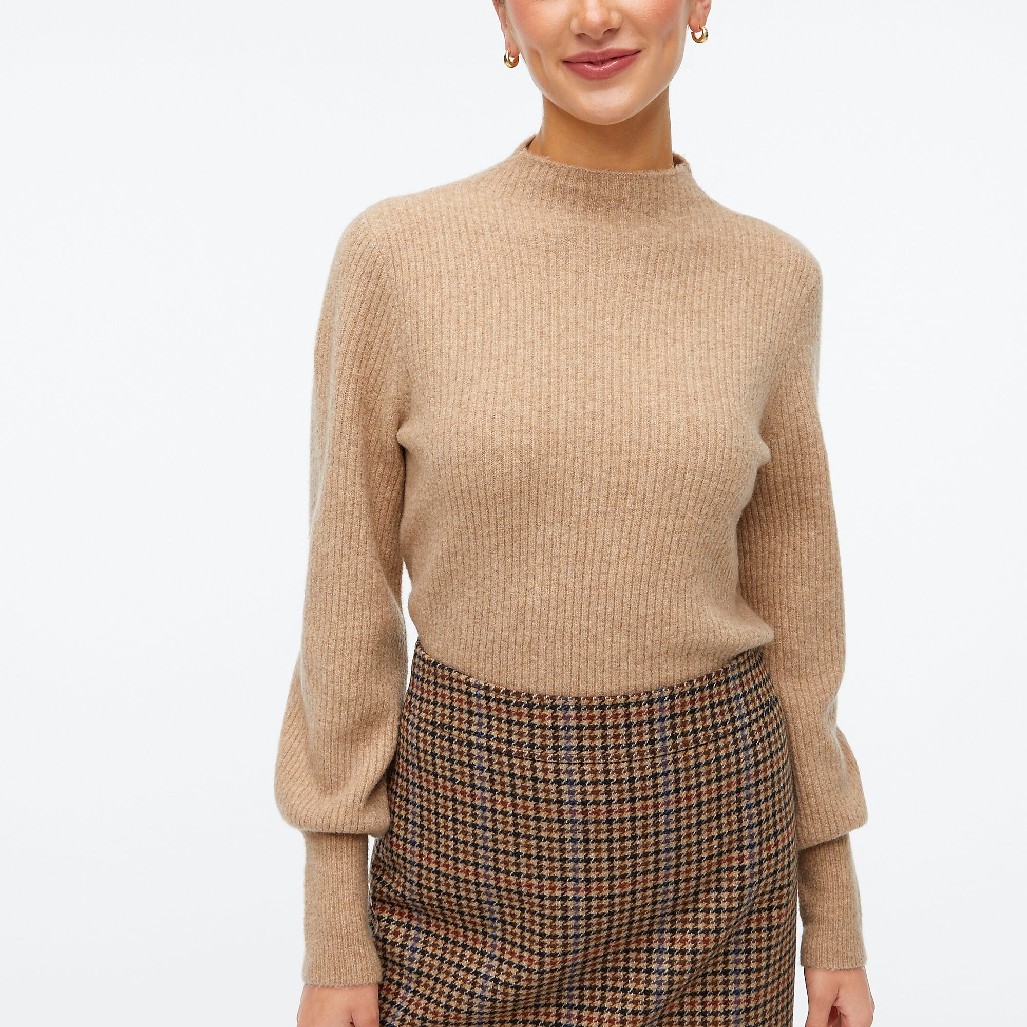 Model wearing tan mock neck sweater with tan,red, and black skirt